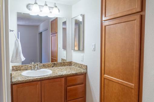 A bathroom with a sink, mirror, and wooden cabinet.