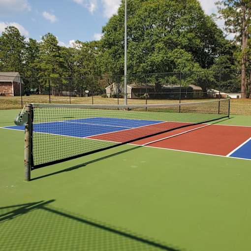 A tennis court with a net and a green pole.