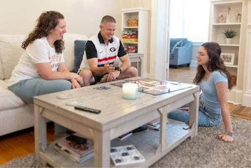 Three people are sitting around a coffee table playing a game.