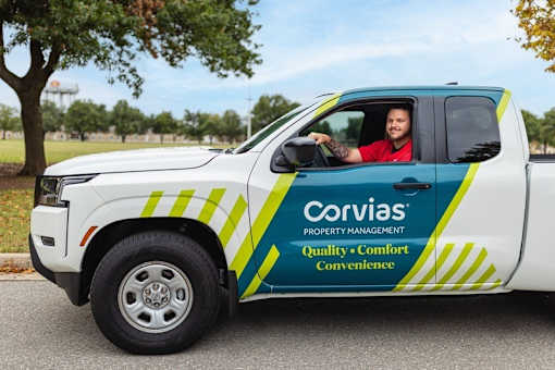 A white truck with a blue and green design and the words "Corvias Property Management" on the side is parked on a street.
