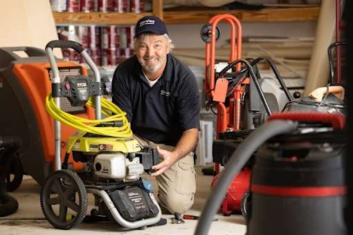 A man in a blue shirt is working on a yellow and black machine.