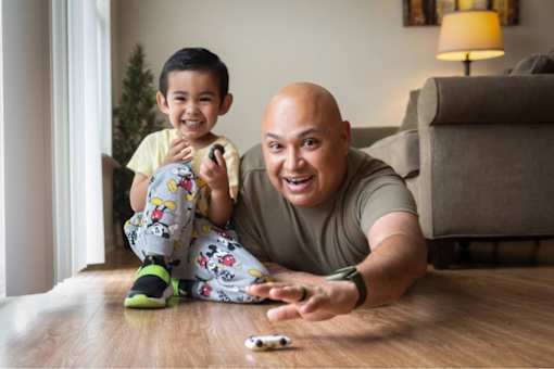 A man and a child are sitting on the floor playing with a toy.