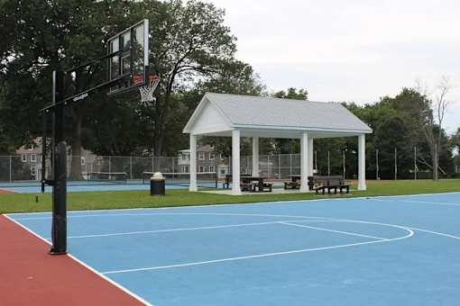 A basketball court with a basketball hoop and a pavilion in the background.