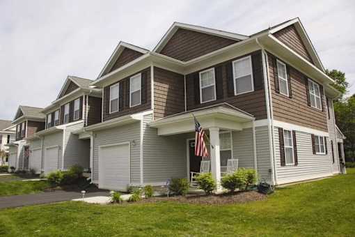 A house with a brown and grey exterior and a flag on the front porch.