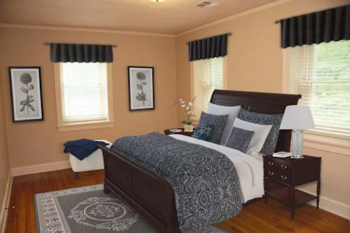 A bedroom with a bed, nightstand, and two framed pictures on the wall.