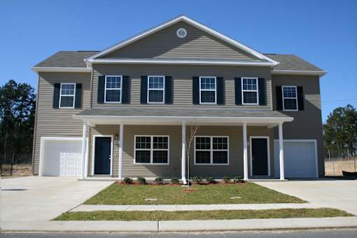 A grey house with black shutters and a white garage door.