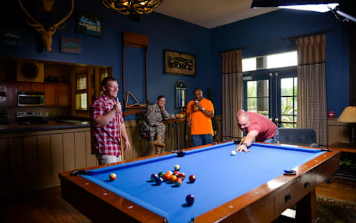 A man is playing pool in a room with blue walls.