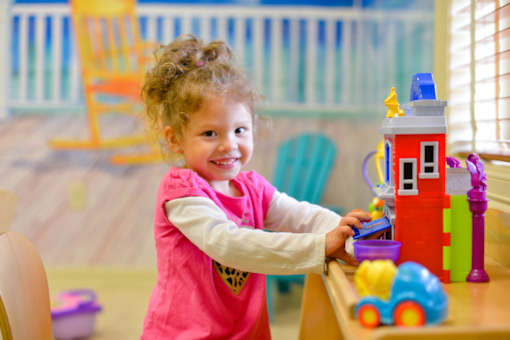 A little girl playing with toys in a playroom.