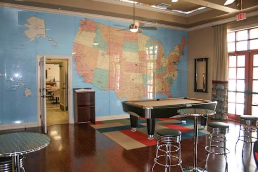 A room with a pool table and a map of the United States on the wall.