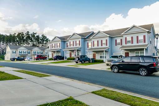 A black SUV is parked on the side of a street in front of a row of houses.