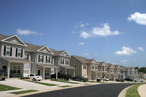A row of houses with cars parked in front.