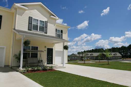 A yellow house with a white porch and a covered patio.