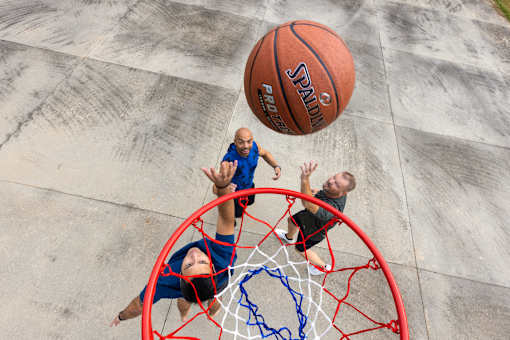 A basketball player in a blue jersey is attempting to block a shot by a player in a black jersey.