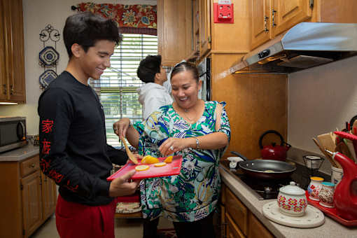 A woman and a boy are preparing food in a kitchen.