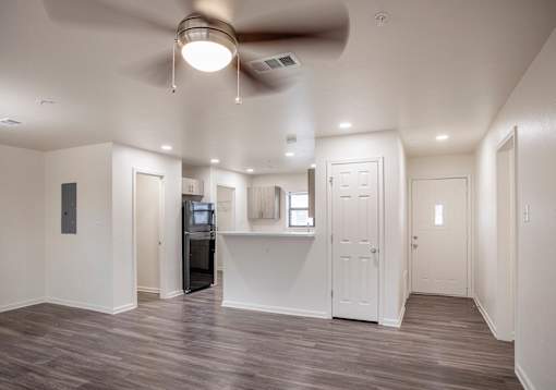 A spacious room with a ceiling fan and a wooden floor.
