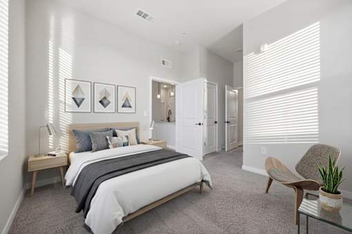A bedroom with a bed, chair, and potted plant.