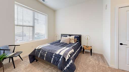 A bedroom with a bed, a chair, and a small table.