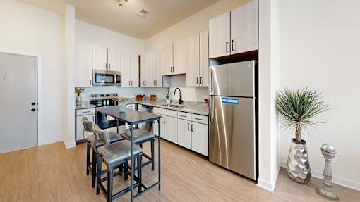A kitchen with a stainless steel refrigerator, a microwave, and a dining table with chairs.