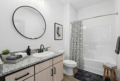 A bathroom with a sink, mirror, toilet, and shower.