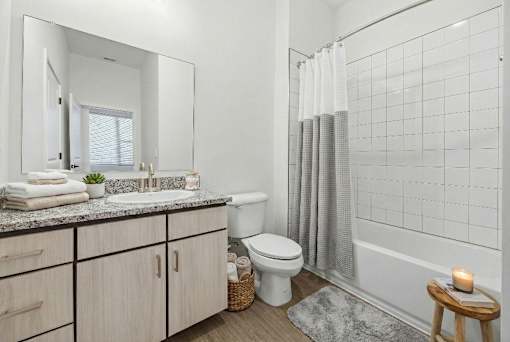 A bathroom with a white toilet, sink, and a small table with a candle on it.