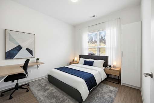 A bedroom with a bed, desk, and chair.