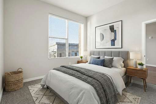 A bedroom with a large bed, a basket, and a framed picture on the wall.