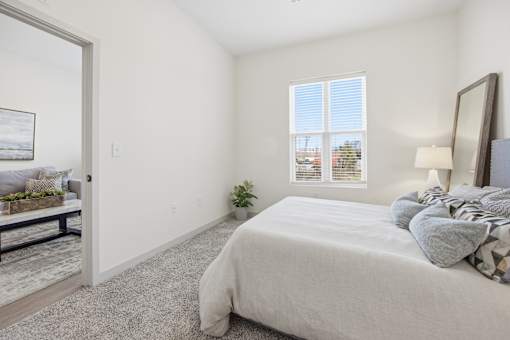A bedroom with a large bed and a window with blinds.