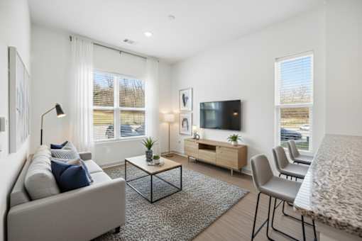 A modern living room with a grey sofa, a black coffee table, a wooden cabinet, and a television.