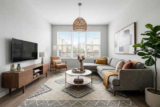 A living room with a grey couch, a wooden cabinet, a coffee table, and a large window.