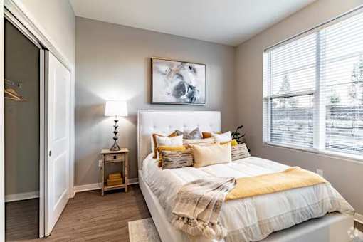 A bedroom with a bed, a nightstand, and a painting on the wall.