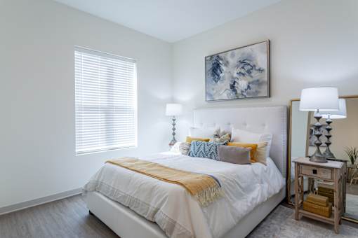 A bedroom with a white bed and a painting above it.