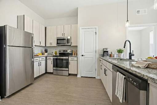 A kitchen with a refrigerator, microwave, oven, and sink.