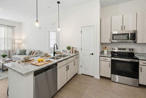 A modern kitchen with a granite countertop and stainless steel appliances.