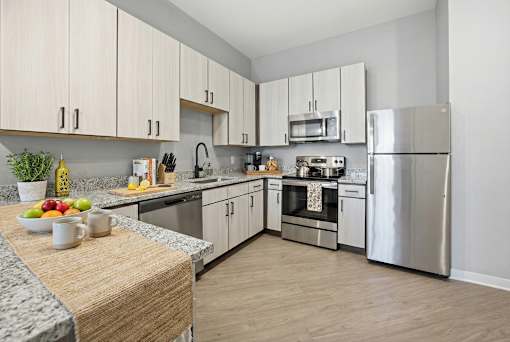 A kitchen with a refrigerator, oven, and sink.