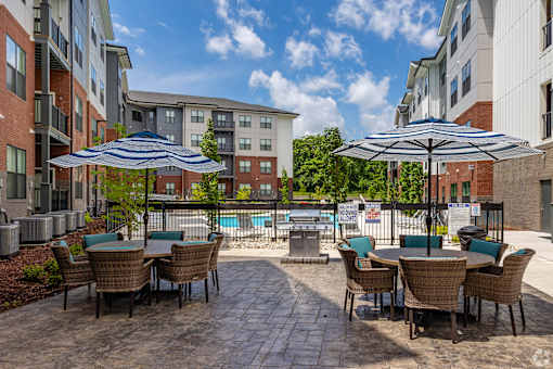 A patio with chairs and umbrellas overlooking a pool.
