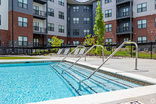 A swimming pool in front of a multi-story apartment building.