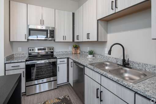A modern kitchen with granite countertops and stainless steel appliances.