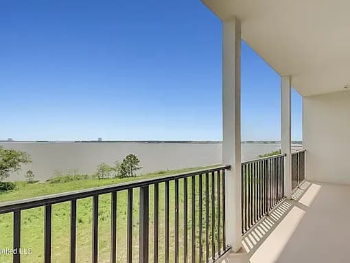 A balcony with a view of a body of water and trees.