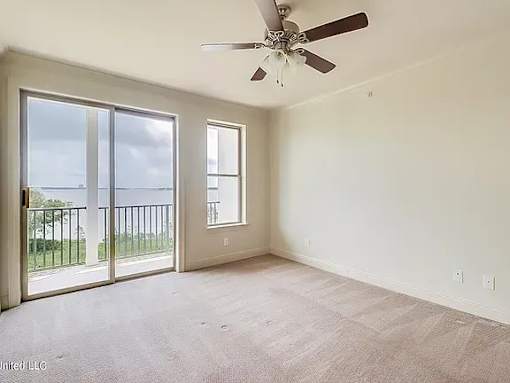 A room with a ceiling fan and sliding glass doors.