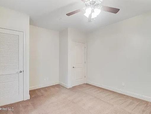 A room with a ceiling fan and two doors.