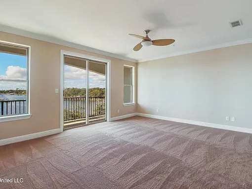 A room with a ceiling fan and sliding glass doors.