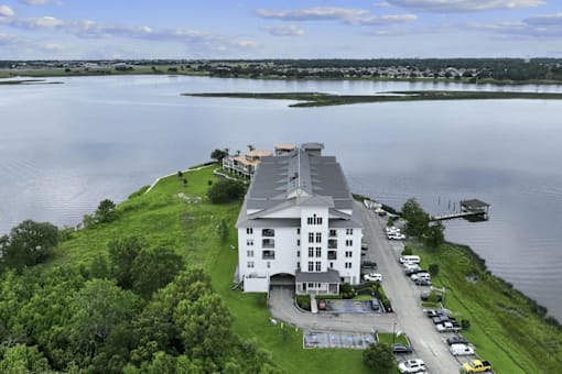 A large white building sits on a grassy area next to a body of water.
