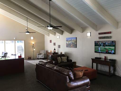 A seating area with a brown leather couch, a brown leather chair, and a television.