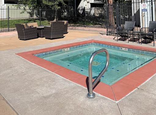 A hot tub with pool chairs beside it.