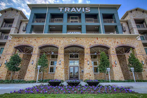 The Travis Leasing building is made of stone and has a green awning.
