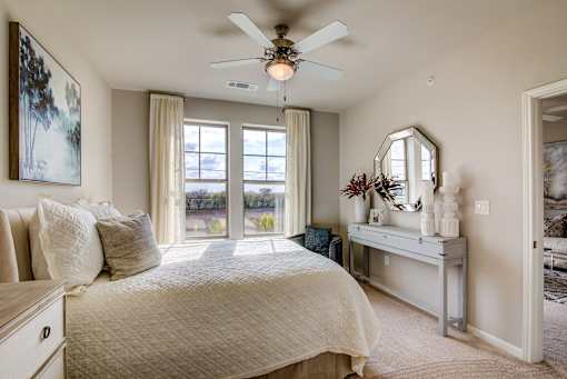 A bedroom with a large bed and a ceiling fan.