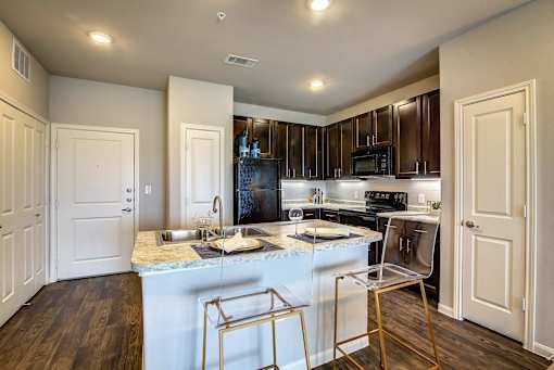 A kitchen with a white island and a black refrigerator.
