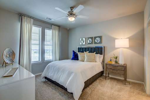 A bedroom with a bed, nightstand, and a ceiling fan.