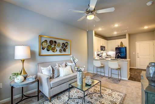 A living room with a grey couch, a coffee table, and a painting on the wall.