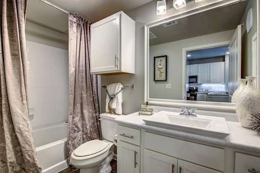 A white bathroom with a toilet, sink, and a mirror.